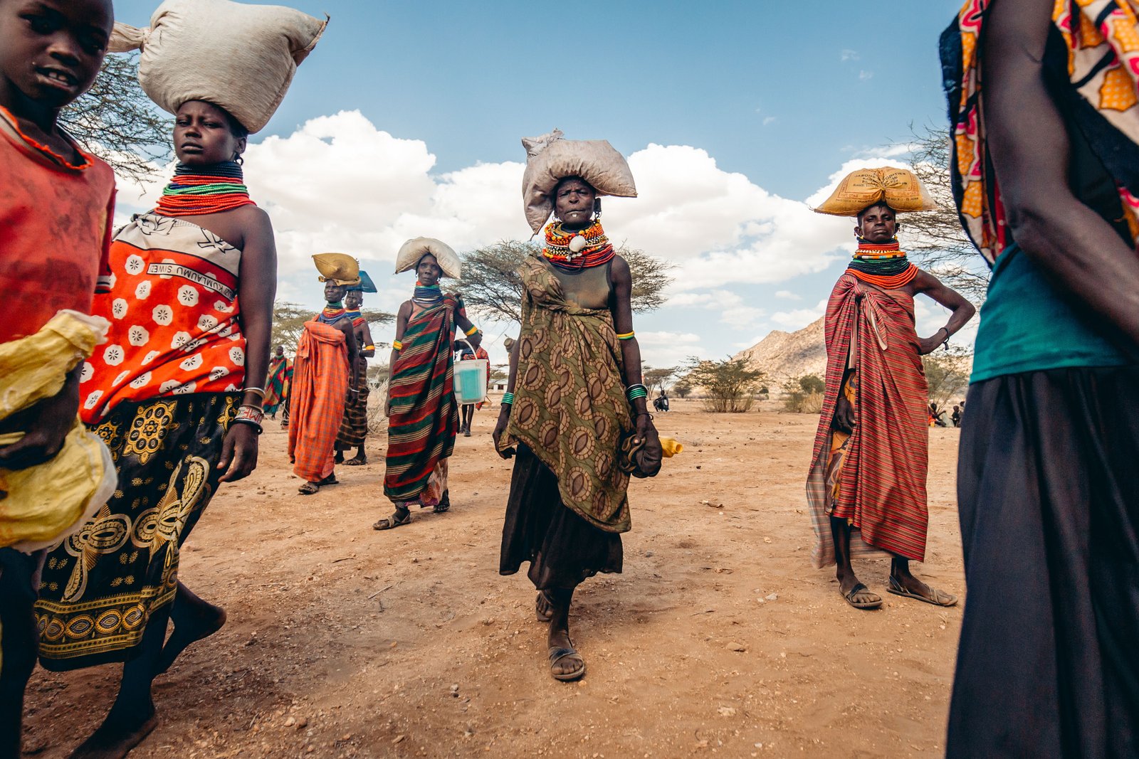 Women in traditional dress walking through an arid landscape in northern Kenya
